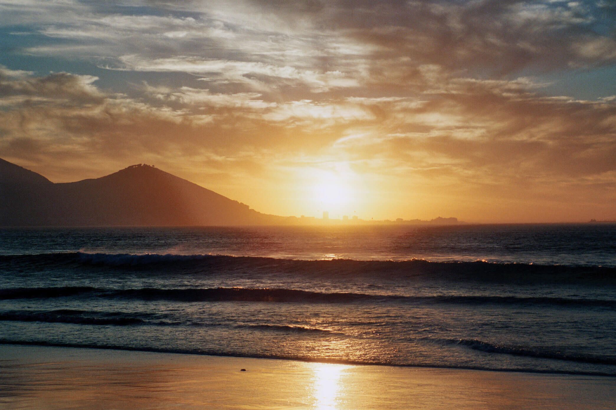 Südafrika, Sonnenuntergang am Sunset Beach in Kapstadt mit Blick auf Signal Hill und Waterfront.