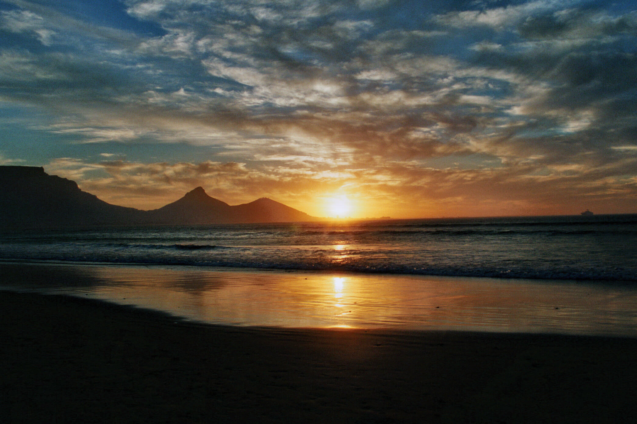 Südafrika, Sonnenuntergang am Sunset Beach in Kapstadt mit Blick auf Tafelberg, Lion's Head, Signal Hill und Waterfront.
